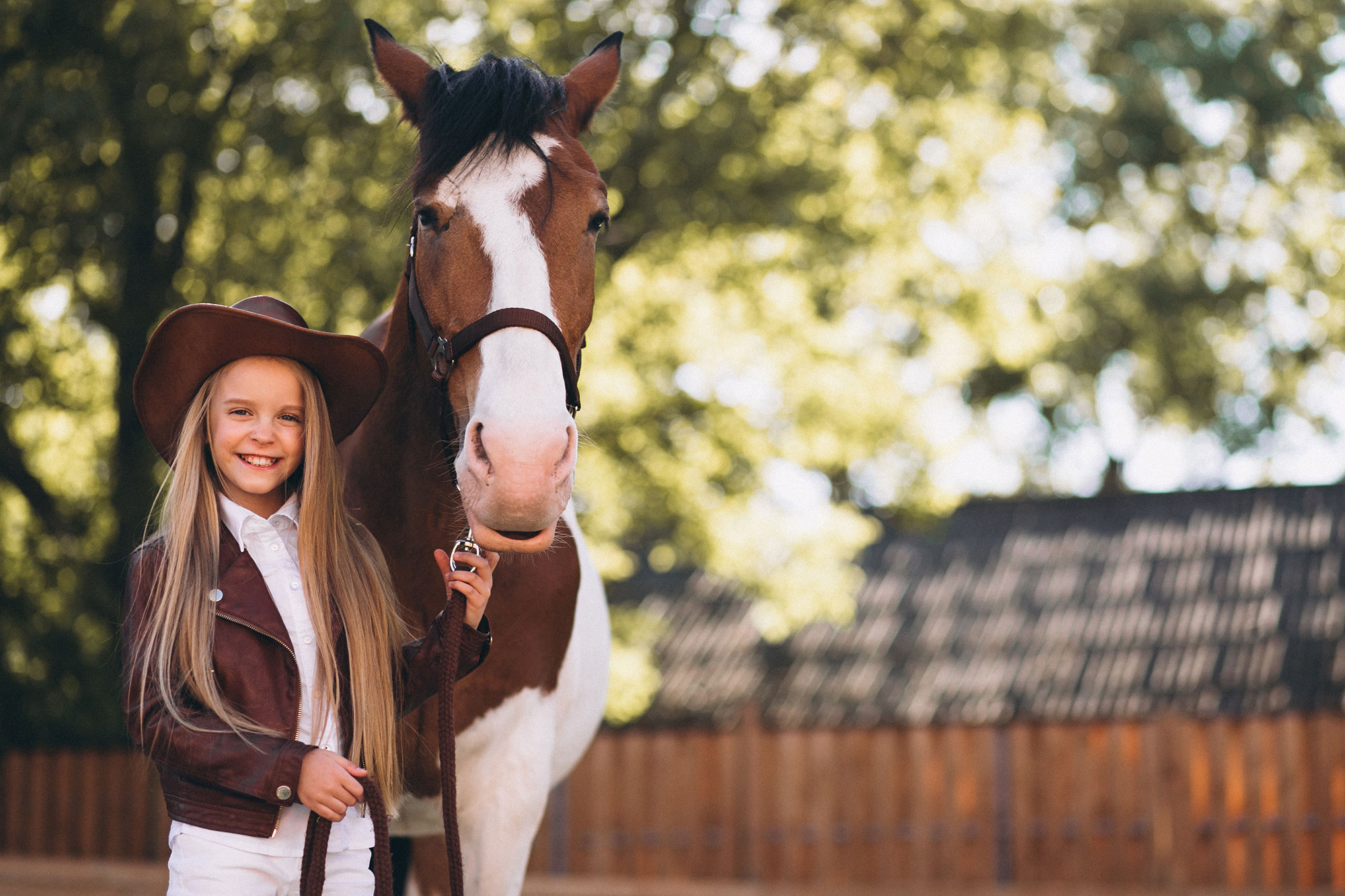 Dievčatko s cowboy klobúkom a koňom na ranči